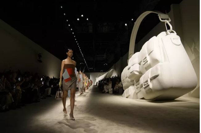 По бокам подиума были выставлены огромные слепки сумок Fendi, которые своими открывающимися клапанами образовывали арки или фоны для VIP-персон и влиятельных лиц, которые могли сфотографироваться по прибытии.